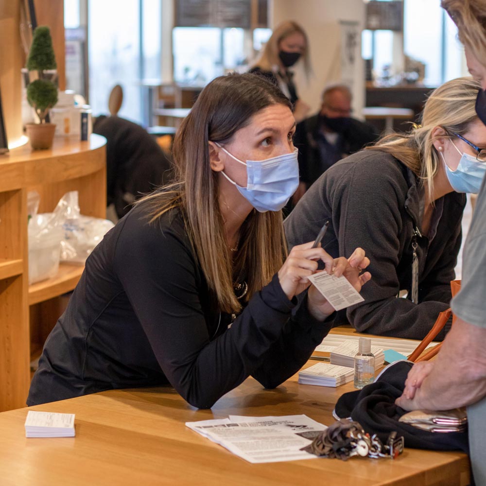 A healthcare worker wearing a mask and helping a patient with some paperwork.