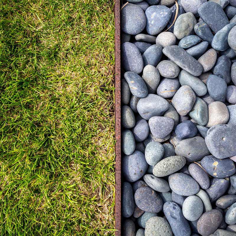 A close up photo split in half vertically, with grass on one side and pebbles on the other.