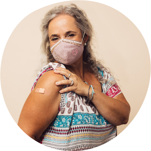 older woman wearing mask showing she received her covid-19 vaccination