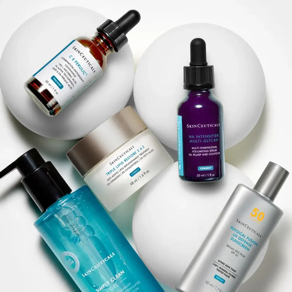 Five SkinCeuticals skincare products, including serums, moisturizer, cleanser, and sunscreen, are arranged on white circular platforms against a white background.