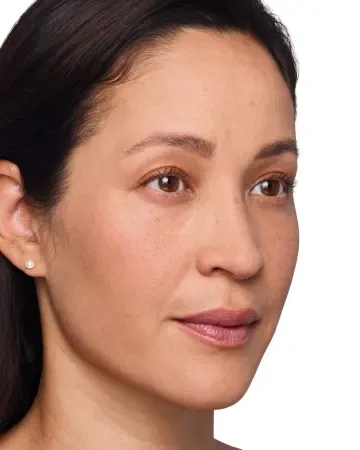 A woman with medium skin tone, straight dark brown hair, and brown eyes looks slightly to the right. She has natural makeup, a neutral expression, and wears a small stud earring. The background is white.